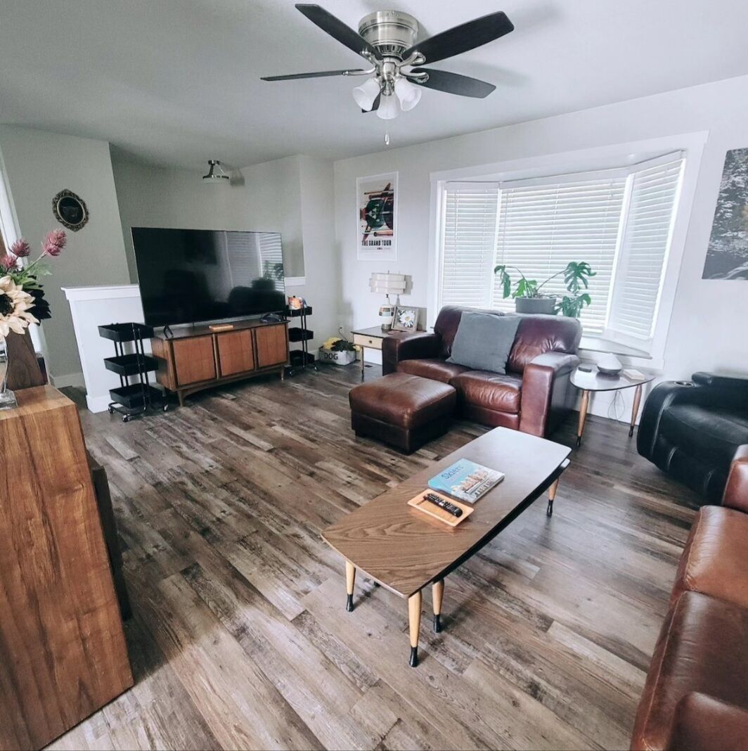 Ein Wohnzimmer mit Couch aus Leder, Fernseher und einem Holztisch.