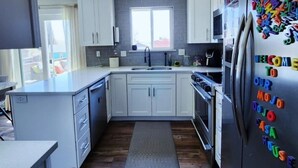 A modern kitchen with white cabinets, a stainless steel refrigerator, and a window above the sink. - Pikes Peak Panorama View (Colorado Springs)