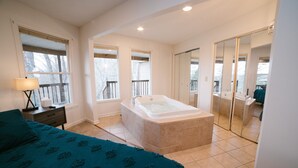 A bedroom with a large bed, a bathtub, and a walk-in closet. - Hickory Hill Round House: Indoor POOL, mins from South Holston River, with view  (Bluff City)