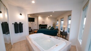 A spacious bathroom with a large bathtub, a mirror, and a television mounted on the wall. - Hickory Hill Round House: Indoor POOL, mins from South Holston River, with view  (Bluff City)