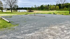 An empty parking lot with gravel surface, surrounded by grassy areas and trees. - Full hookups and WIFI RV spots  (Jerusalem)