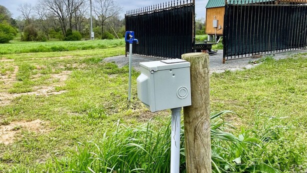A rural setting with a fenced area, a wooden structure, and a utility box. - Full hookups and WIFI RV spots  (Jerusalem)