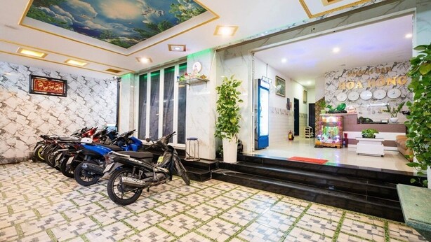 A hotel lobby with a tiled floor, a ceiling mural, a reception area, and a motorcycle parking area. - Hoa Hong Hotel (Ho Chi Minh City)