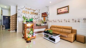 A reception area with a marble wall, a reception desk, a sofa, and a coffee table. - Hoa Hong Hotel (Ho Chi Minh City)