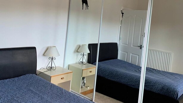 A room with two beds, a mirror, a nightstand, and a lamp.