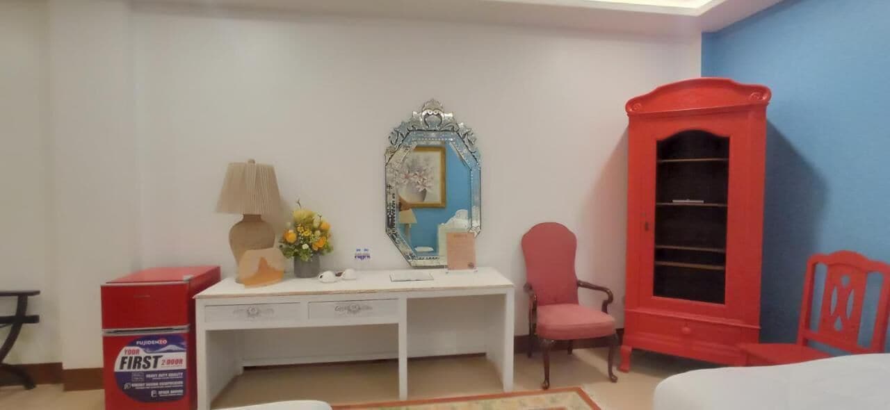 Een kamer met een wit bureau, een spiegel, een rode stoel, een rode kast en een rode garderobekast.