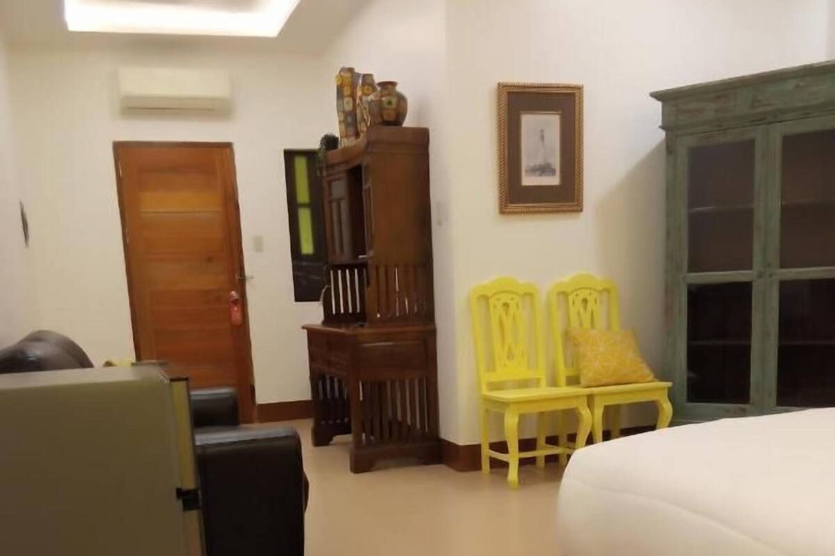 Une chambre à coucher comprenant un lit, une armoire, un bureau et deux chaises.