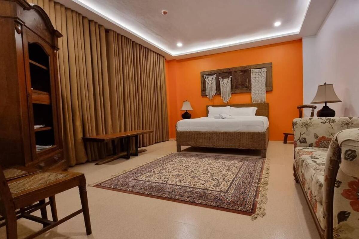 Une chambre à coucher comprenant un lit, un canapé, une armoire en bois et un tapis à motifs.