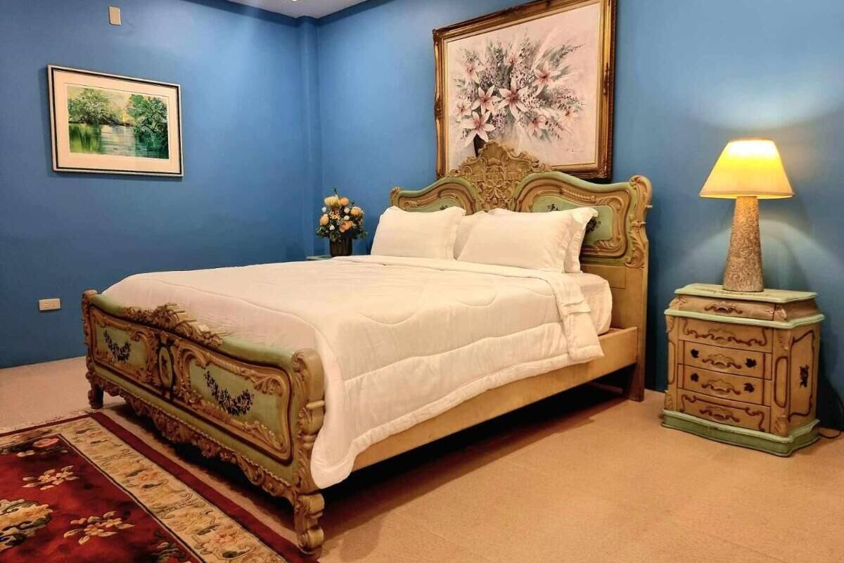 Une chambre à coucher avec un grand lit, une table de chevet, une lampe et deux tableaux encadrés au mur.