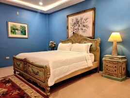 A bedroom with a large bed, a nightstand, a lamp, and two framed pictures on the wall.