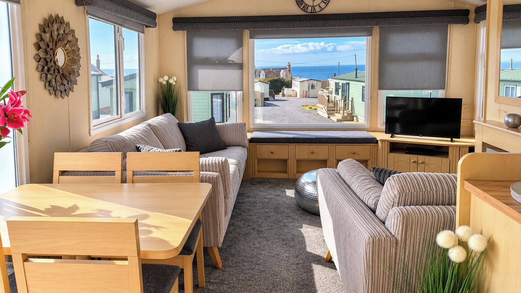 A caravan interior with a dining area, sofa set, and a television.