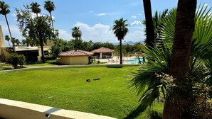 A residential area with a swimming pool, palm trees, and a clear sky.