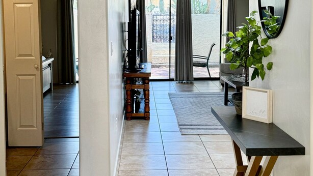 A modern interior with a hallway leading to a dining area, a ceiling fan, and a large window.