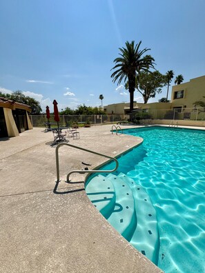 Una piscina con sombrilla, una tumbona y una palmera.