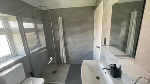 Een moderne badkamer met douche, toilet en wastafel.