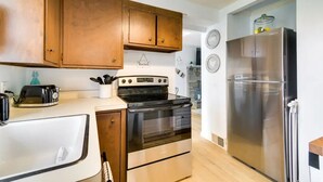 Une cuisine avec des meubles de rangement en bois, un réfrigérateur en acier inoxydable, une cuisinière et un évier.