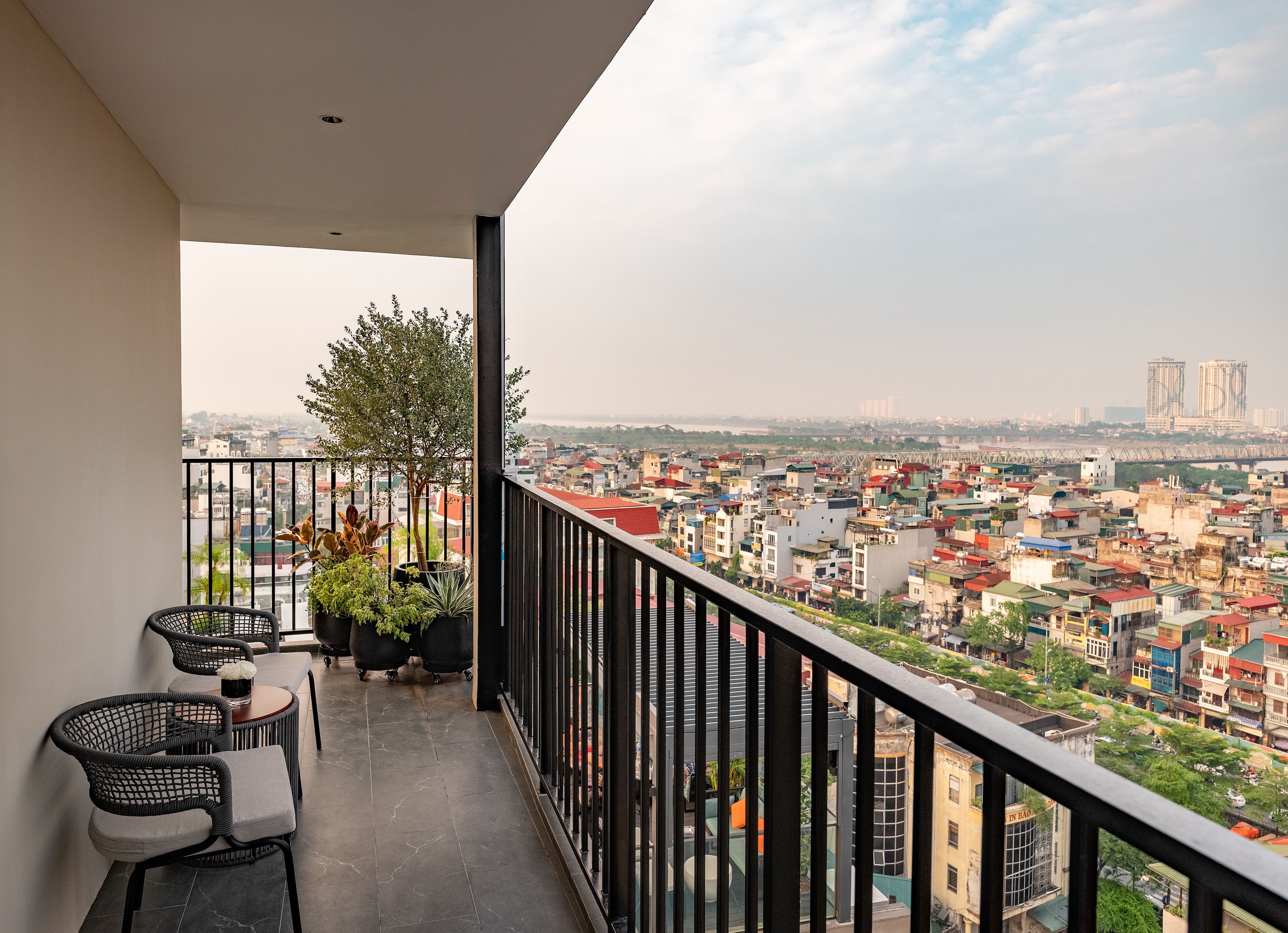 A balcony with a view of a cityscape, including buildings and a bridge.