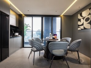 A modern dining area with a glass partition, a table with chairs, and a view of the cityscape. - CLASSYC Hotel (Hanoi)
