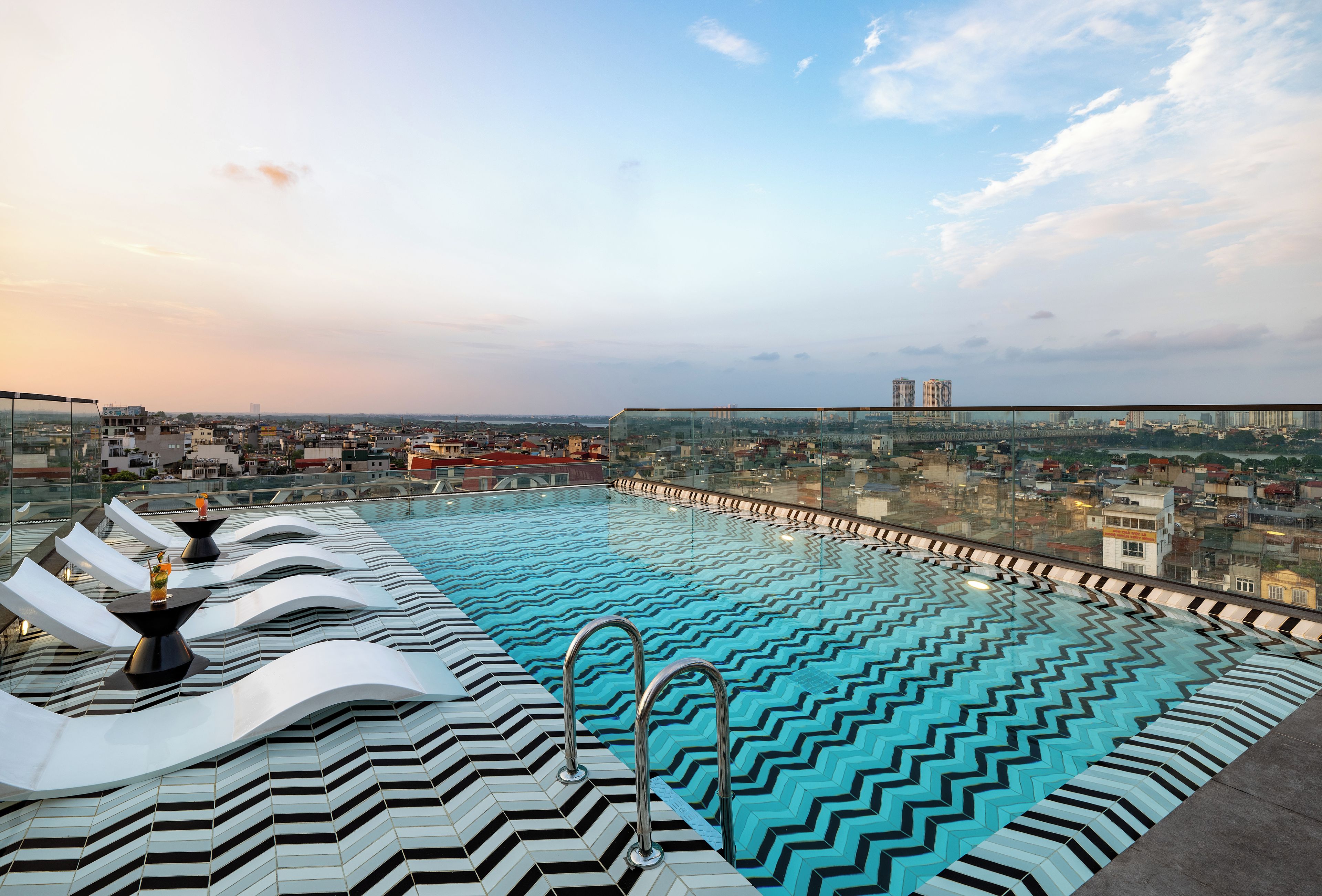 A rooftop infinity pool with a city view, surrounded by modern architecture.