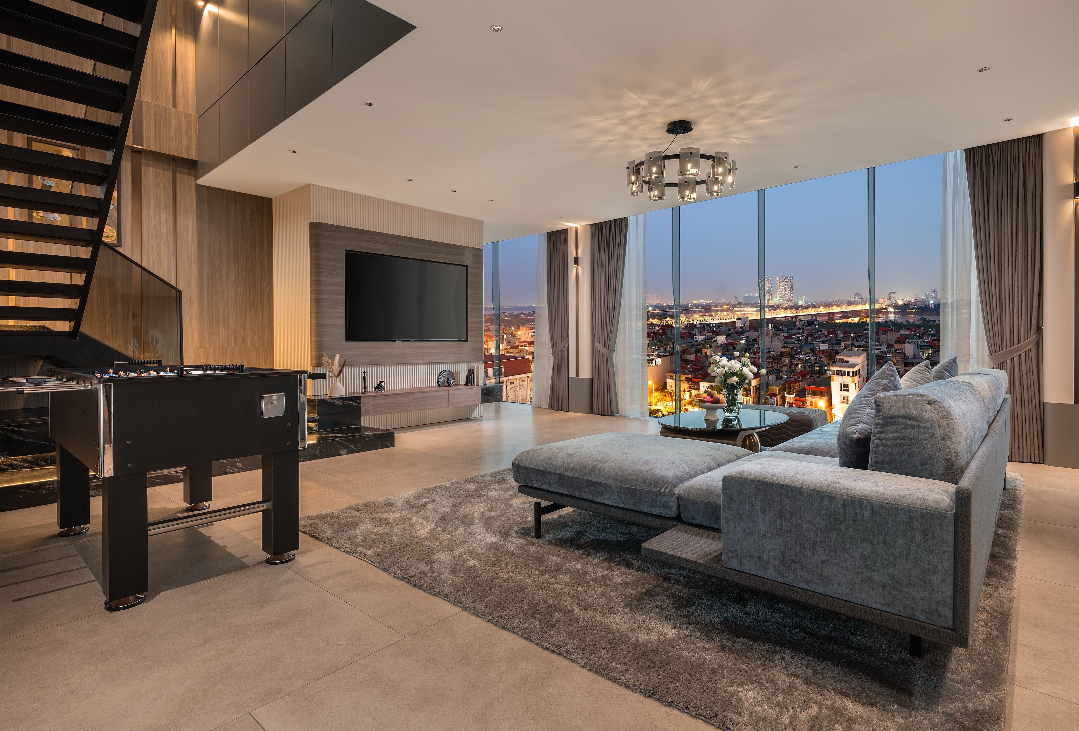 A modern living room with a sofa, a coffee table, a TV, and a foosball table.