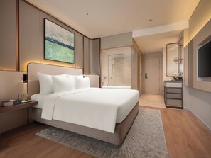 A modern hotel room with a large bed, a bedside table with a lamp, a TV, and a shower area. - CLASSYC Hotel (Hanoi)