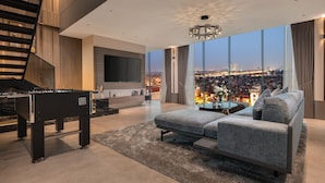 A modern living room with a sofa, a coffee table, a TV, and a foosball table. - CLASSYC Hotel (Hanoi)
