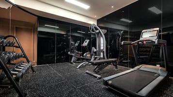A modern gym with a variety of equipment including dumbbells, a treadmill, and weight machines.