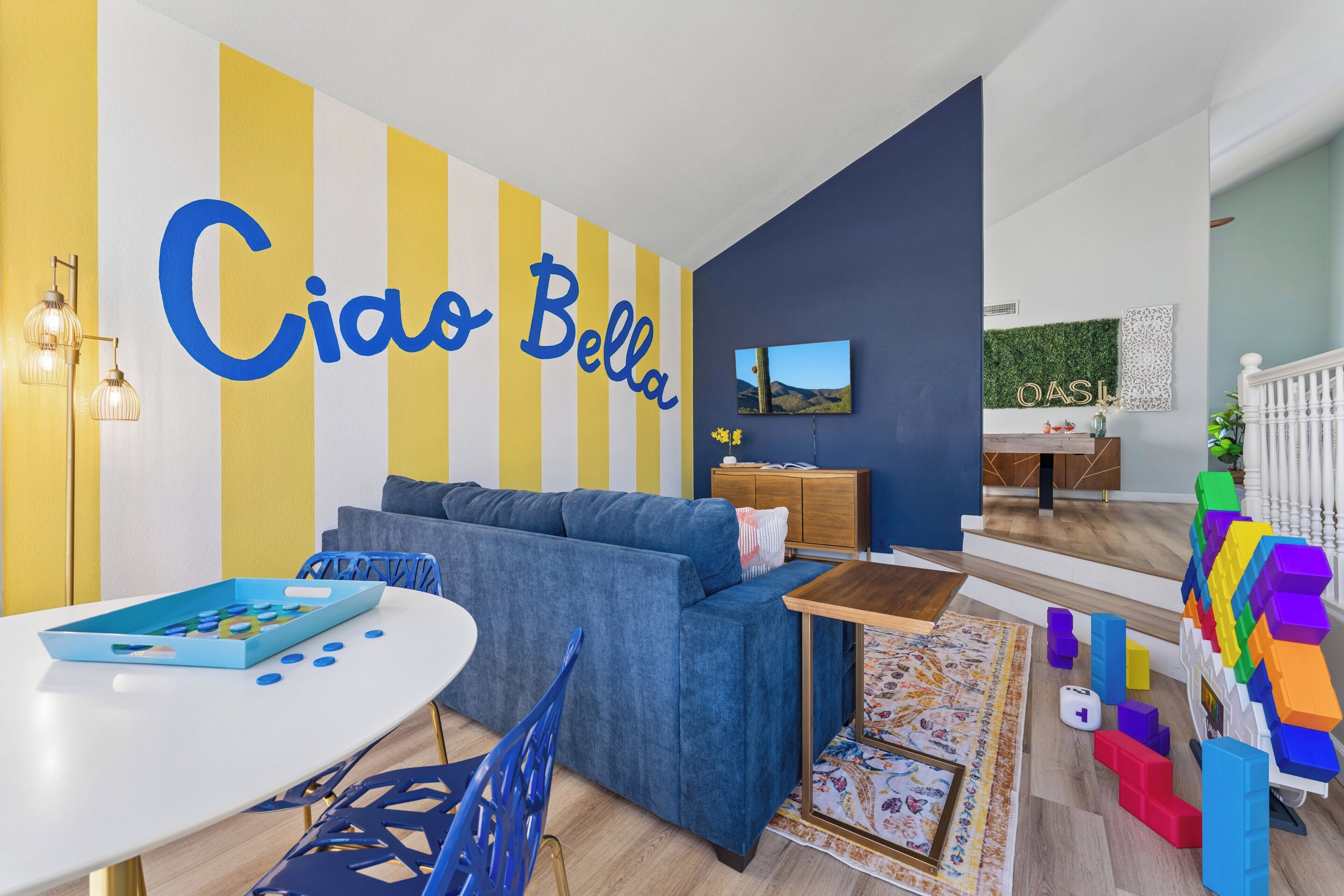 Una sala de estar moderna con un sofá azul, una mesa blanca y un espacio de juego colorido.