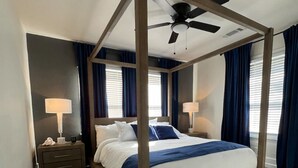 Un lit à baldaquin avec un ventilateur de plafond, une tête de lit en bois et une table de chevet avec une lampe.