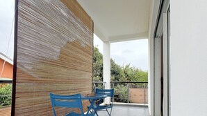 A covered outdoor area with a modern design, featuring a wooden partition and blue chairs. -  E&D Apartment with balcony, Quiet and Secure Ideal For Families (Tananarive)