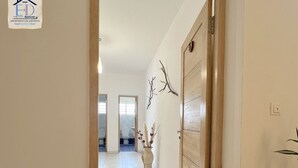 A hallway with a wooden door, a tiled floor, and a wall-mounted plant. -  E&D Apartment with balcony, Quiet and Secure Ideal For Families (Tananarive)