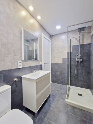A modern bathroom with a white sink, a glass shower enclosure, and a large mirror above the sink. - SR Malagueta, Waterfront, Stunning Ocean View (Malaga)