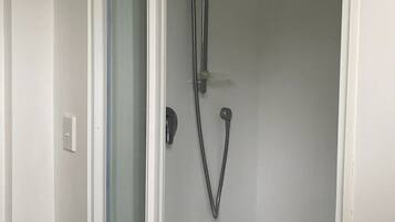 A shower with a glass door, a handheld showerhead, and a wall-mounted faucet.