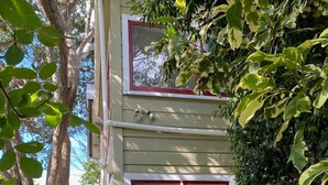 Un edificio de dos pisos con un marco rojo en la ventana y un pequeño porche.