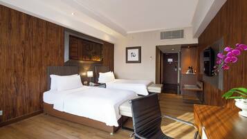A hotel room with two beds, a desk, a chair, a television, and a decorative wall panel.