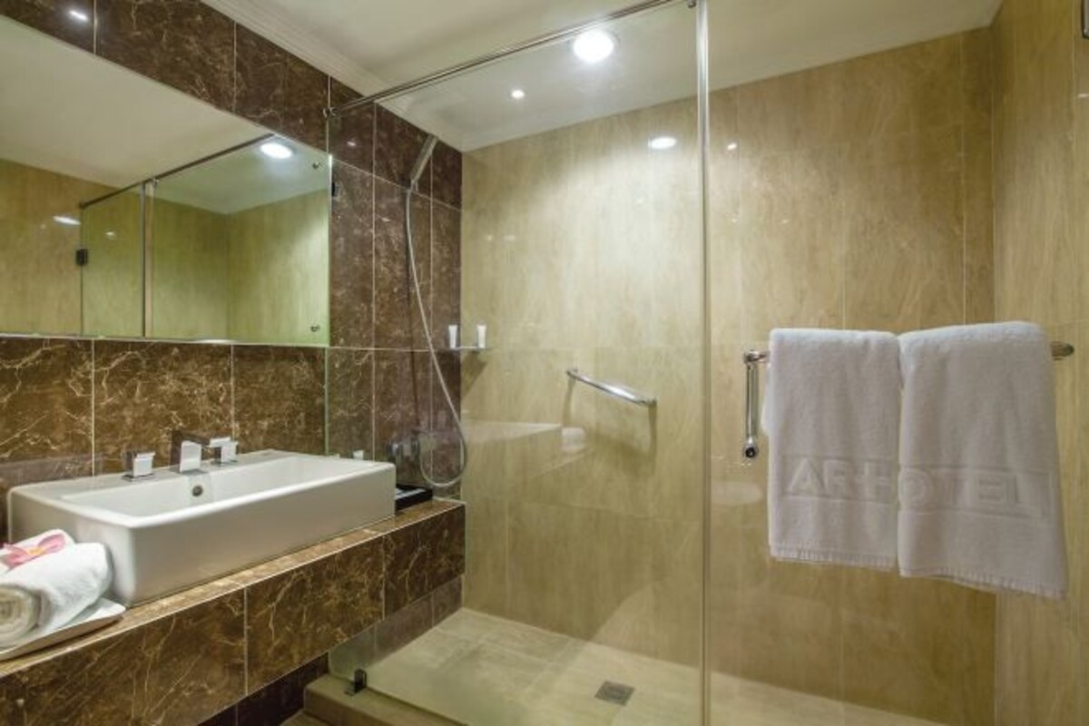 Un baño moderno con un espejo grande, un lavabo y cabina de ducha con mampara de vidrio.