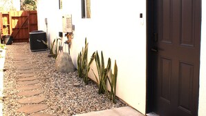Une maison avec une porte sombre, un chemin de pierre et un paillasson orné d’un motif de champignon.