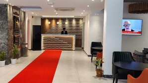 A modern hotel lobby with a reception desk, seating area, and a red carpet. - Hotel omni residency Baridhara (Dhaka)