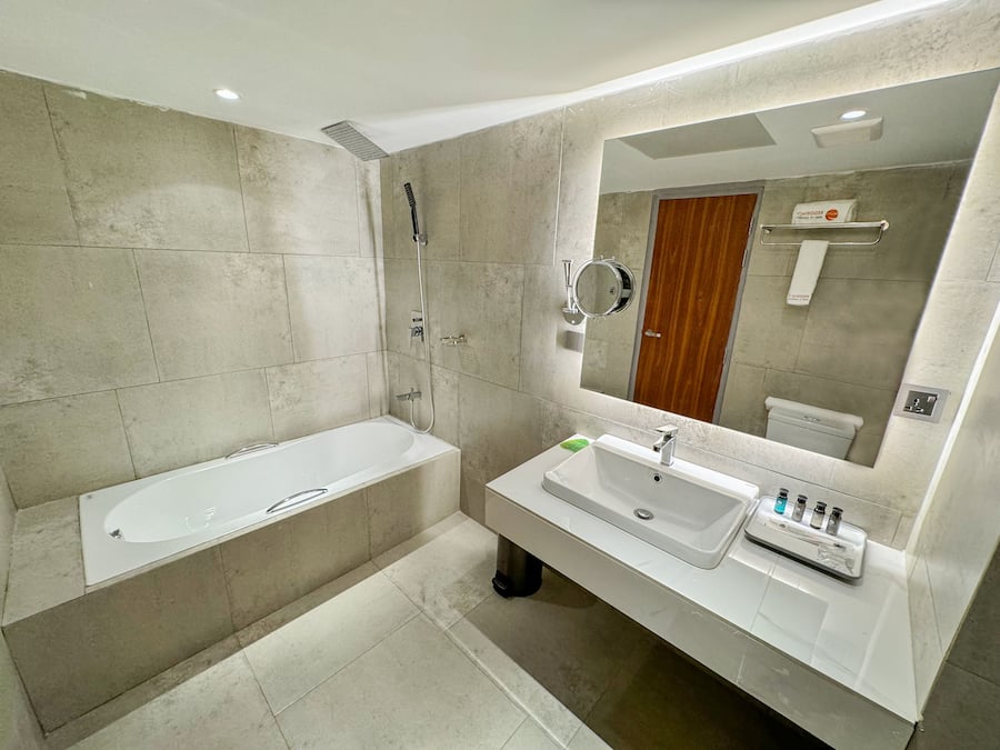 A modern bathroom with a bathtub, a sink, and a large mirror.