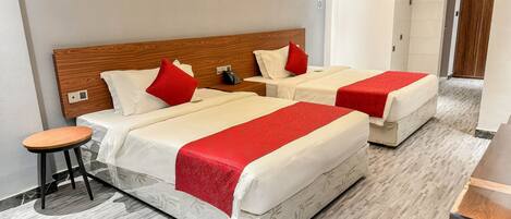 A hotel room with two beds, a small table, and a wardrobe.