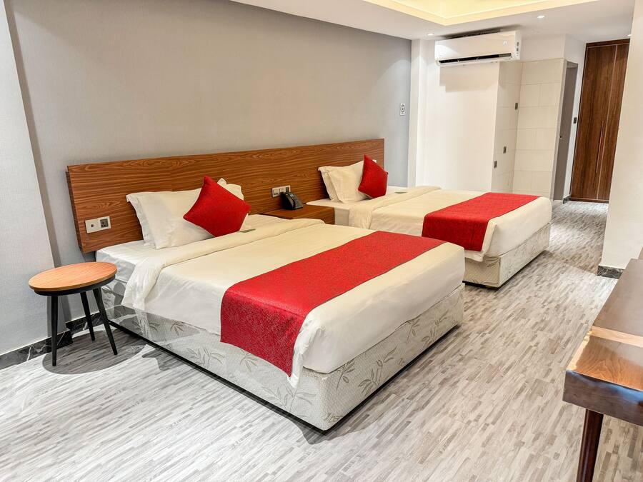 Una habitación de hotel con dos camas, una mesita y un armario.