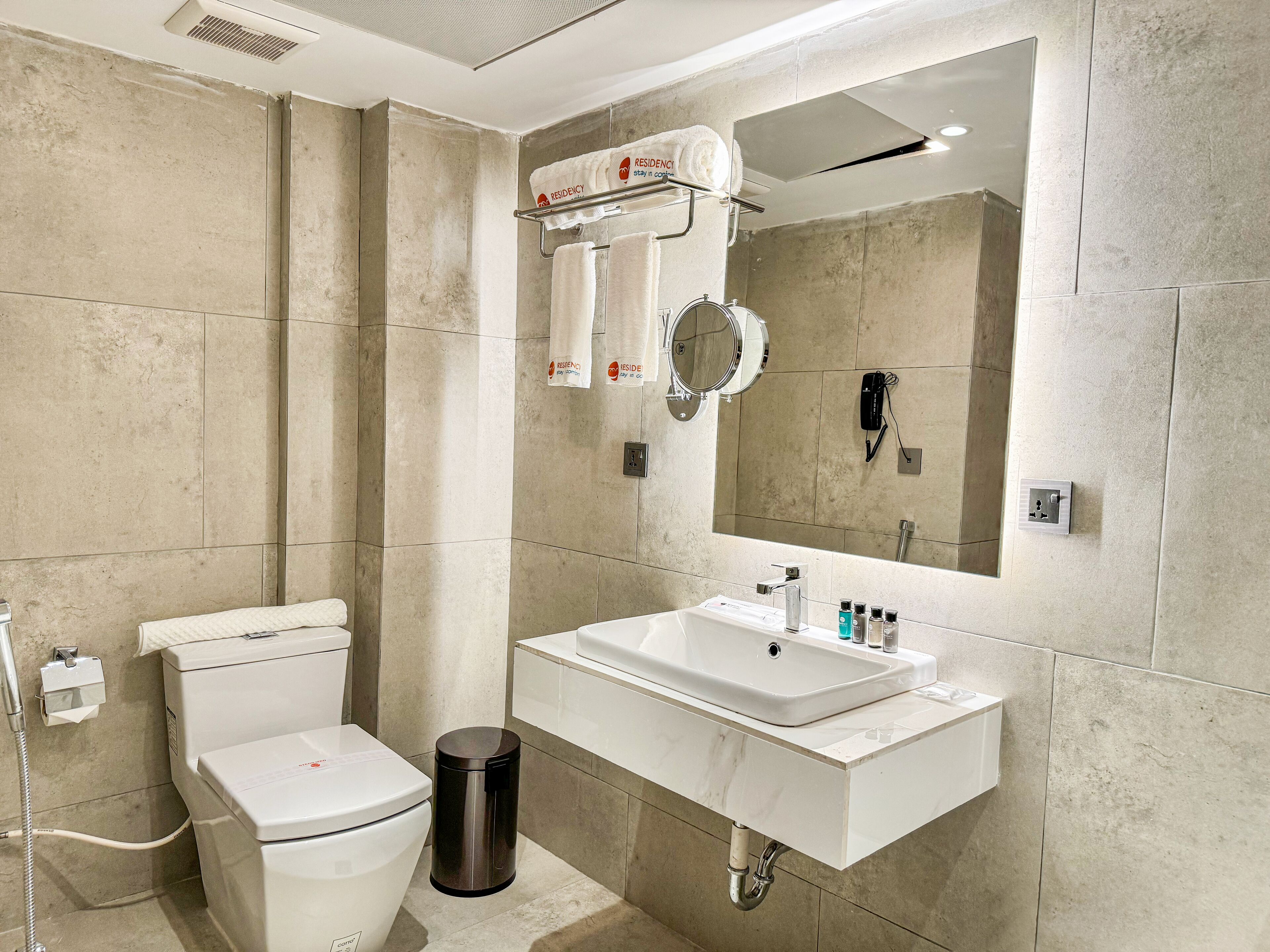 A modern bathroom with a toilet, sink, and mirror.