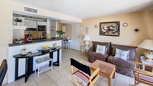 A compact living space with a kitchenette, a dining area, and a seating area with a sofa and chairs.
