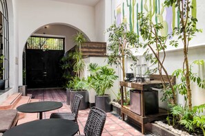 An outdoor patio area with a black gate, potted plants, a wooden table, and chairs. - Santa Casa | Cozy Queen Room in Central Roma Norte (Ciudad de México)