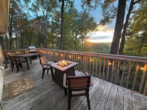 A wooden deck with outdoor furniture and a fire pit, surrounded by trees and a railing. - Shenandoah Twilight | Sunset Views w/ Hot Tub + Fire Table, Near Skyline Drive (Front Royal)