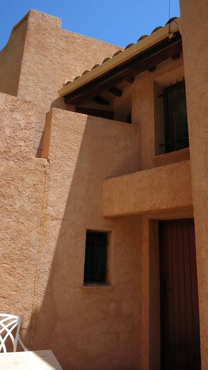 A building with a textured facade, a wooden door, and a small window.
