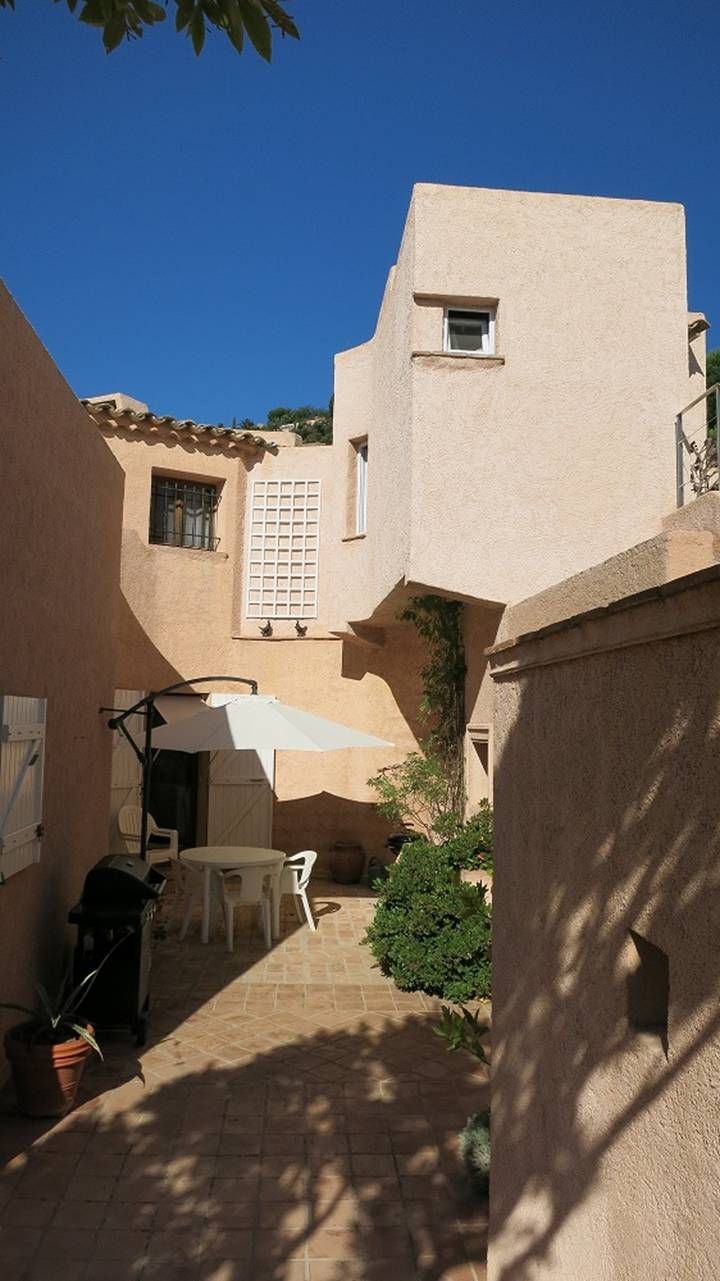 Une cour intérieure avec une table et des chaises, entourée d’immeubles à la façade beige et dotés d’une petite fenêtre.