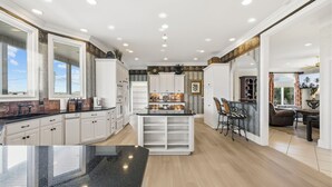 Une cuisine moderne avec des meubles blancs, un îlot central et un coin repas doté d’un bar.