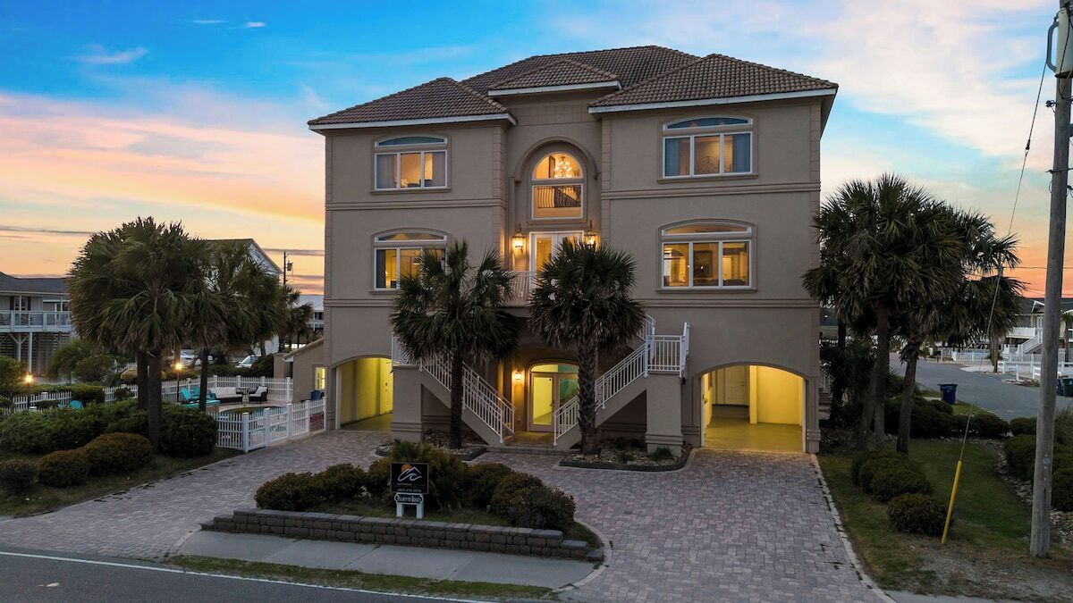 A two-story building with a central entrance, a staircase, and a pool area.