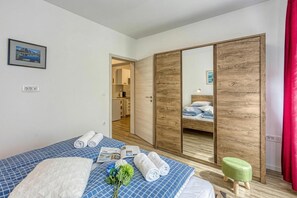 Habitación de hotel con cama, armario de madera, un taburete pequeño y vista a una cocina.